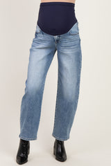 woman wearing light blue maternity jeans with a dark waistband, styled with black ankle boots