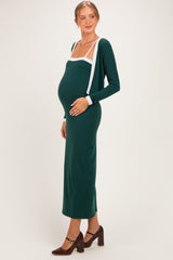 woman wearing a dark green maternity dress with white accent details and a visible baby bump