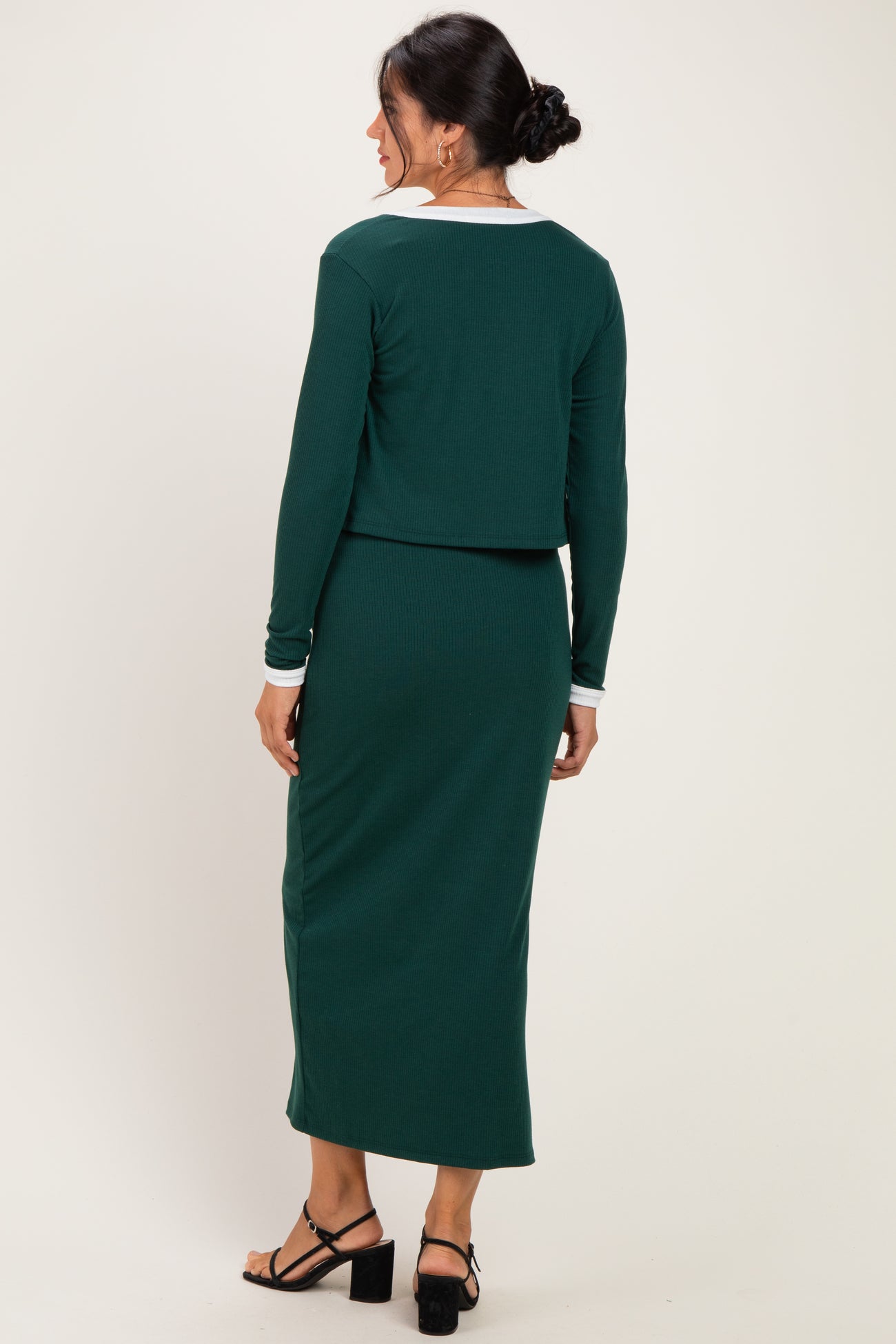 woman wearing a green ribbed two-piece dress with a cropped top and long skirt, showing the back view