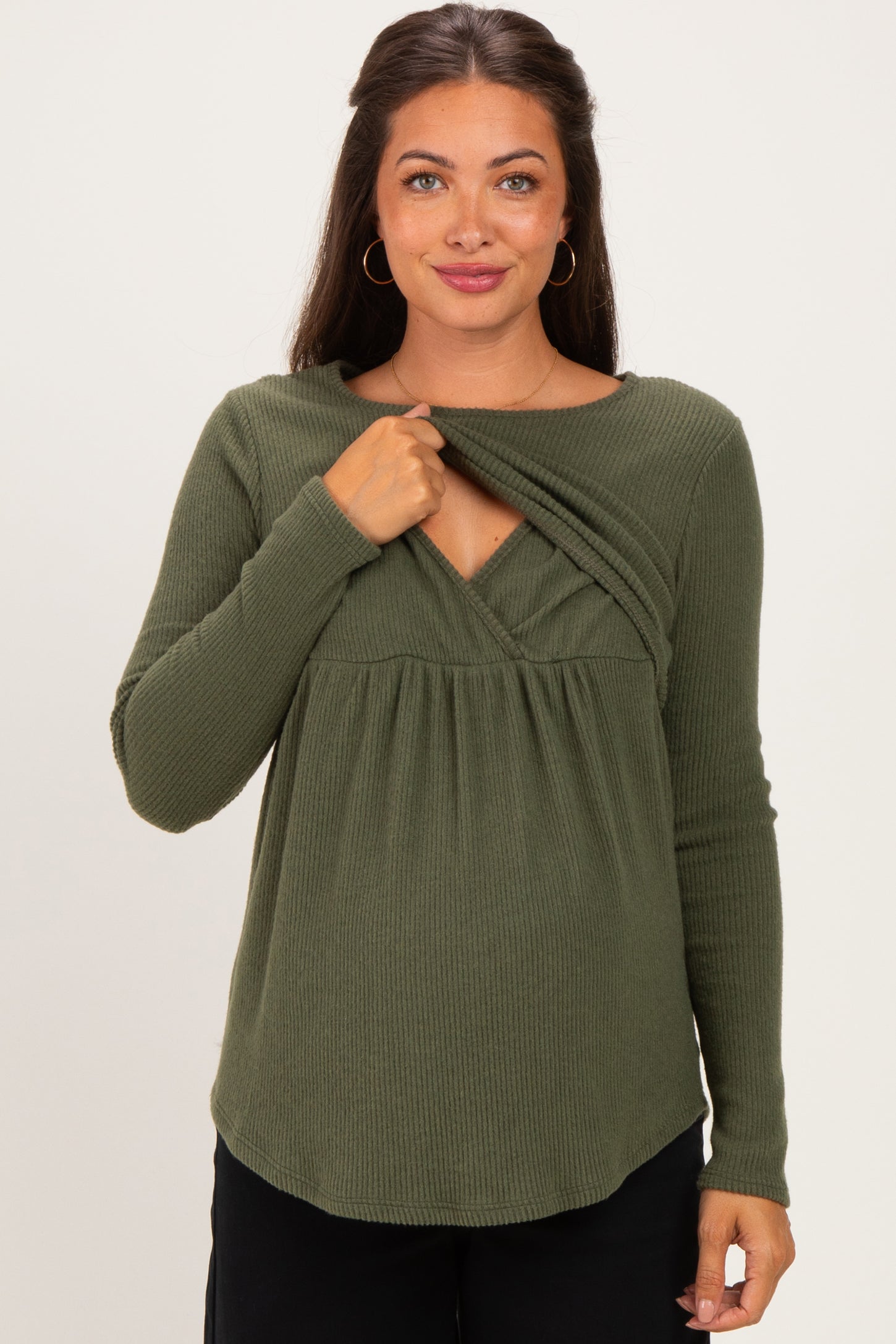 woman wearing a dark green maternity top with a layered front design and long sleeves, highlighting her baby bump