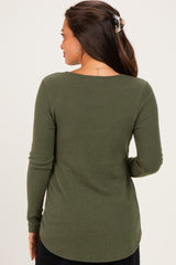 woman wearing a dark green ribbed maternity top, seen from the back, with long sleeves and a rounded hemline
