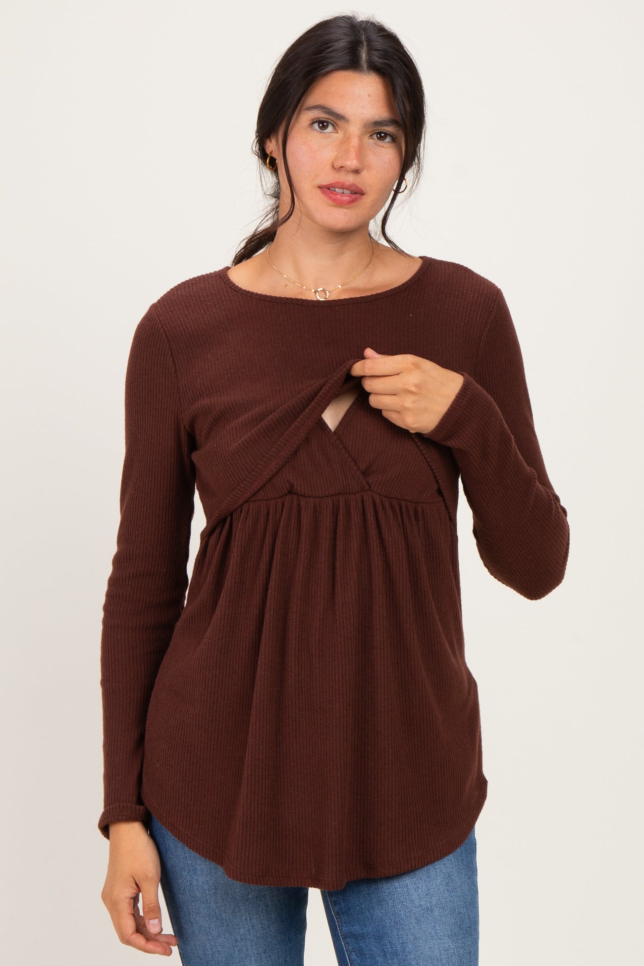woman wearing a brown long sleeve top featuring a twisted front detail and a flared, relaxed fit