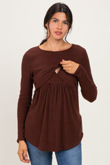 woman wearing a brown long sleeve top featuring a twisted front detail and a flared, relaxed fit
