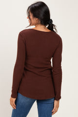 woman wearing a brown ribbed long sleeve top with a slight scoop back and paired with blue jeans