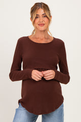 woman wearing a brown long sleeve maternity top and holding her baby bump