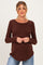 woman wearing a brown long sleeve maternity top and holding her baby bump