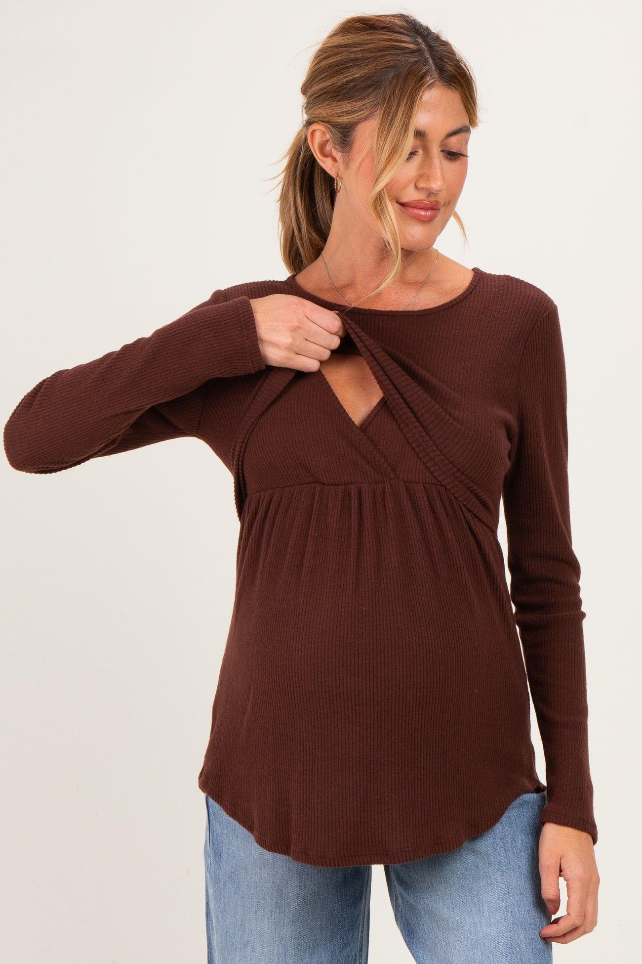 woman wearing a brown ribbed maternity top with a v-neck and lifting design to accommodate breastfeeding, showing her baby bump