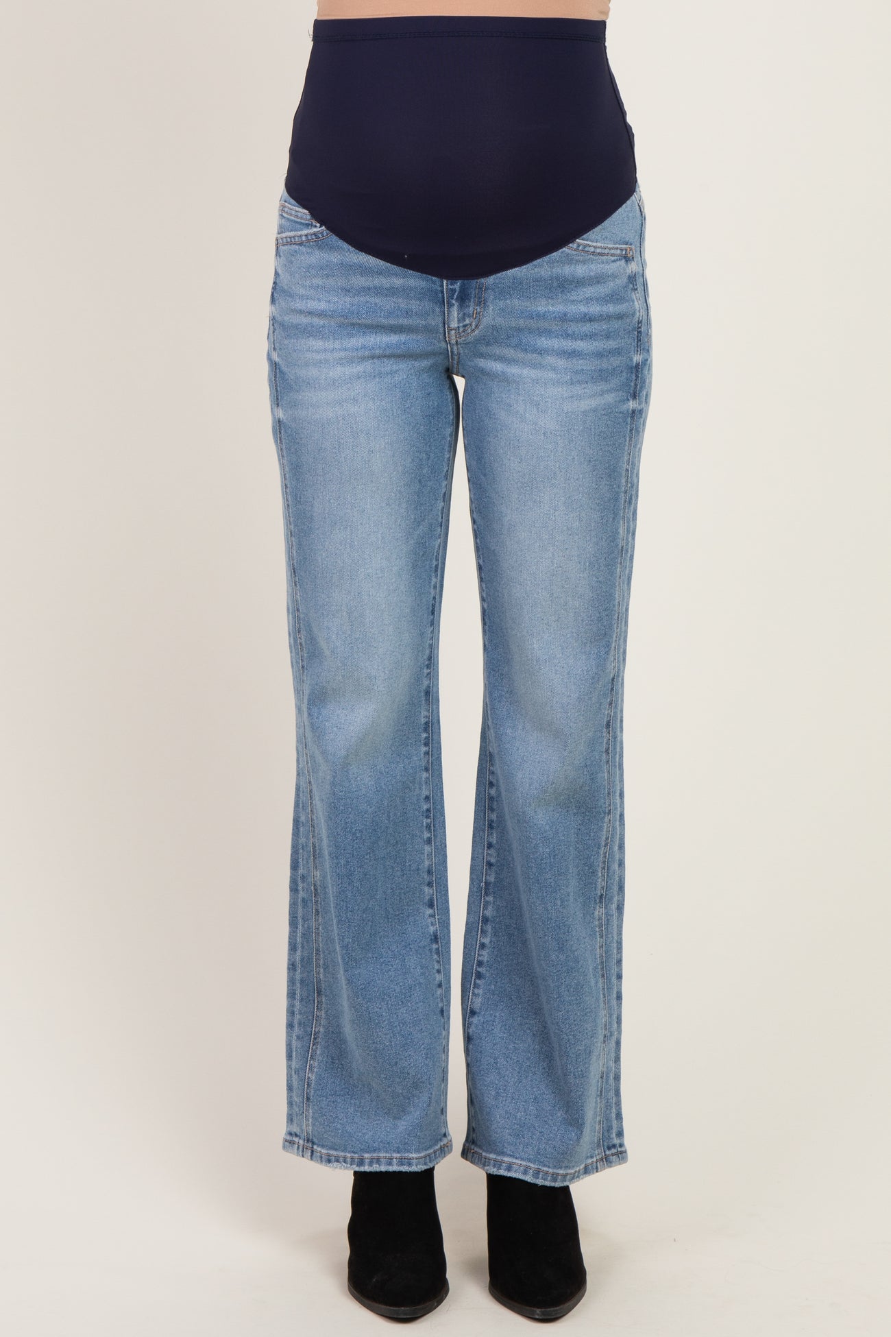 woman wearing light wash flared maternity jeans with a navy blue over-the-bump panel