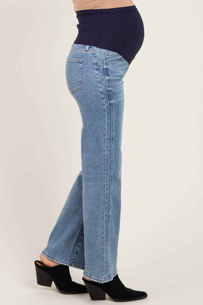 woman wearing light blue maternity jeans with a navy belly panel, showcasing a visible baby bump