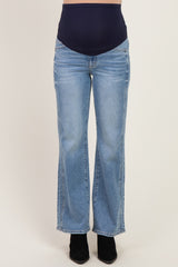 woman wearing light wash flared maternity jeans with a navy blue over-the-bump panel