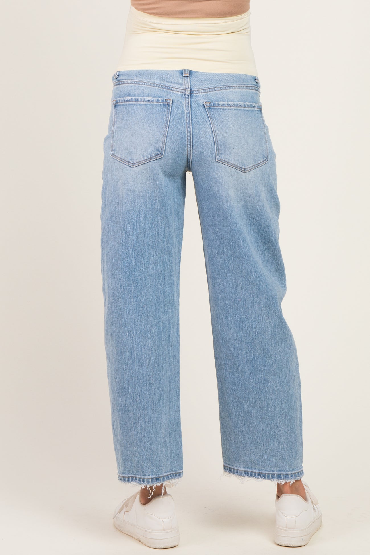 woman wearing light wash maternity jeans with a high waistband and relaxed fit, showing the back view
