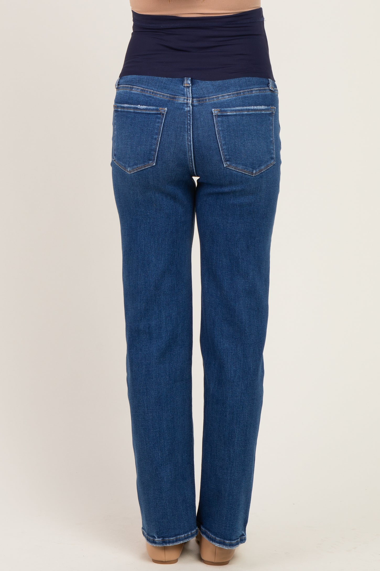 woman wearing a pair of dark blue maternity jeans with a stretchy waistband, viewed from the back