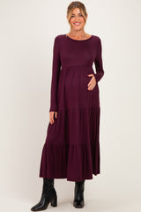 woman wearing a burgundy long sleeve maternity dress with tiered ruffles and holding her baby bump