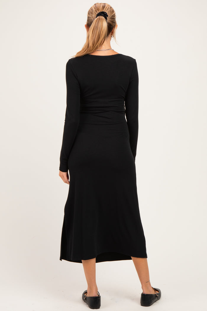 woman wearing a black long sleeve maternity dress with a side slit, viewed from the back