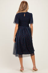 woman wearing a navy blue floral print maternity dress with short flutter sleeves and a smocked bodice