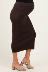 woman wearing a brown ribbed maternity skirt, highlighting her baby bump, paired with beige block-heeled sandals