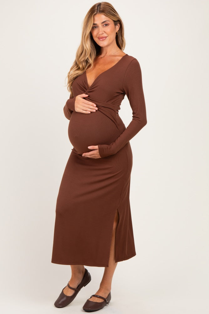 woman wearing a brown long sleeve maternity dress with a side slit and holding her baby bump