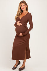 woman wearing a brown long sleeve maternity dress with a side slit and holding her baby bump