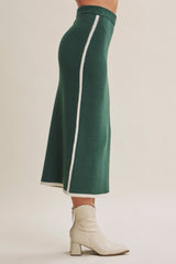 woman wearing a dark green midi skirt with contrasting white side stripes and paired with ankle boots