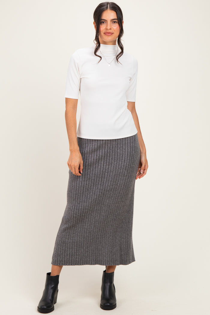 woman wearing a white short sleeve turtleneck top and a gray ribbed midi skirt, paired with black ankle boots
