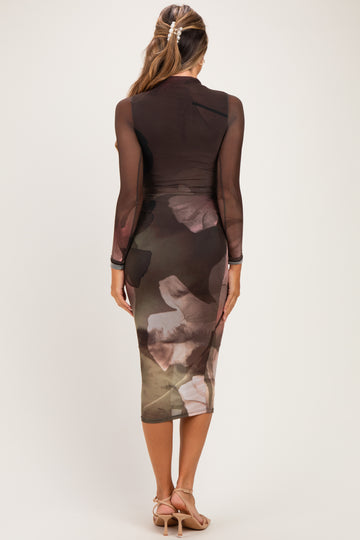 woman wearing a sheer long sleeve maternity dress with a floral print and fitted silhouette, showing a baby bump
