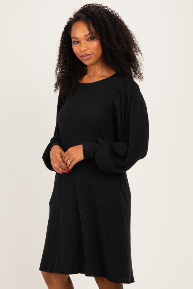 woman wearing a black ribbed long sleeve sweater dress with balloon sleeves and pockets
