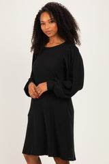 woman wearing a black ribbed long sleeve sweater dress with balloon sleeves and pockets