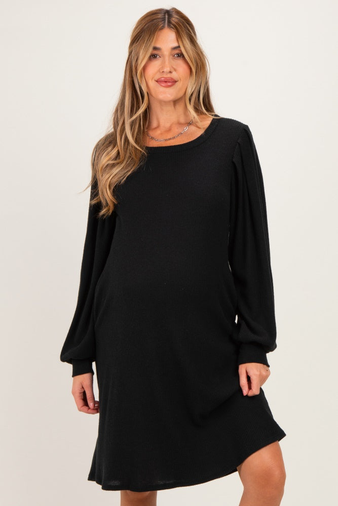woman wearing a black maternity dress with long puff sleeves and a relaxed fit, showing her baby bump