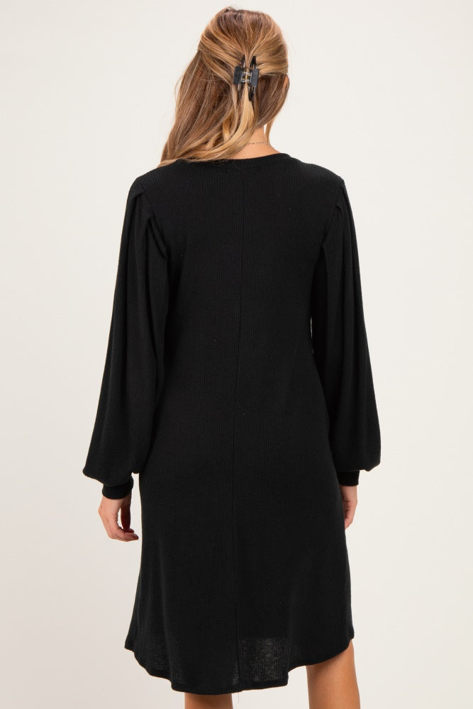 woman wearing a black ribbed maternity dress with long sleeves, viewed from the back