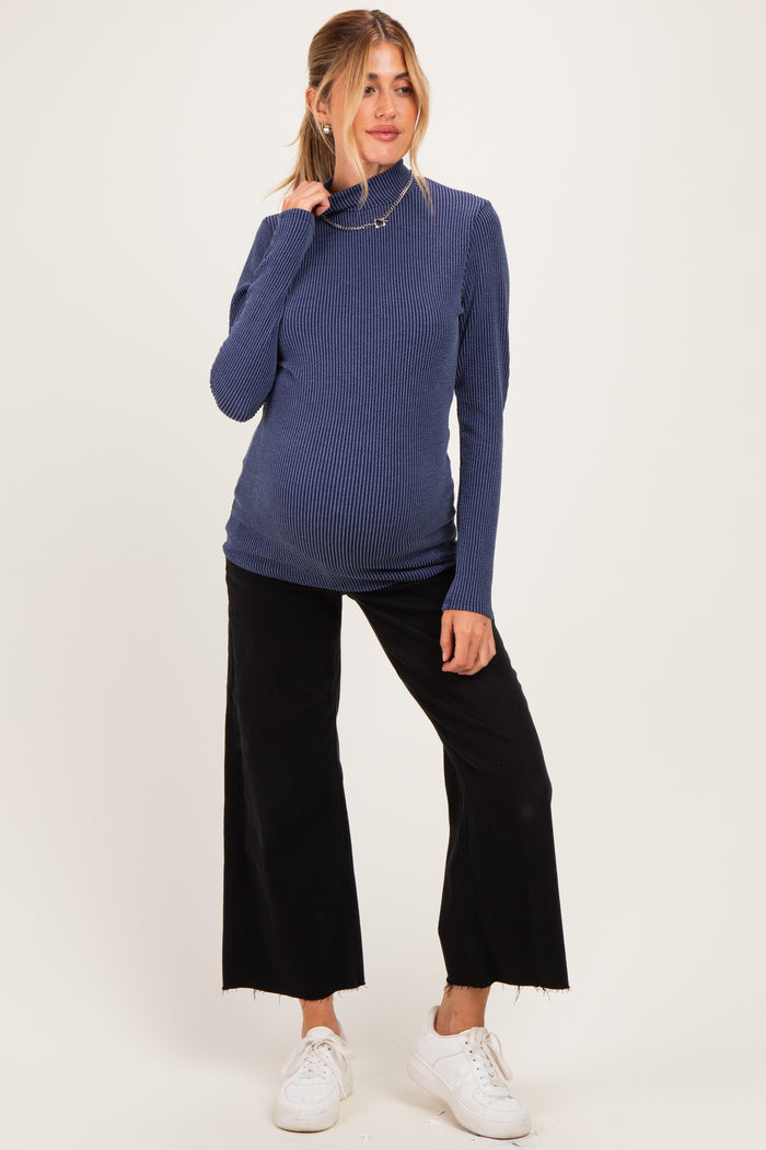 woman wearing a navy ribbed maternity turtleneck top and black wide-leg pants with a visible baby bump