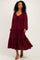 woman wearing a burgundy tiered maxi dress with a tie front and long sleeves