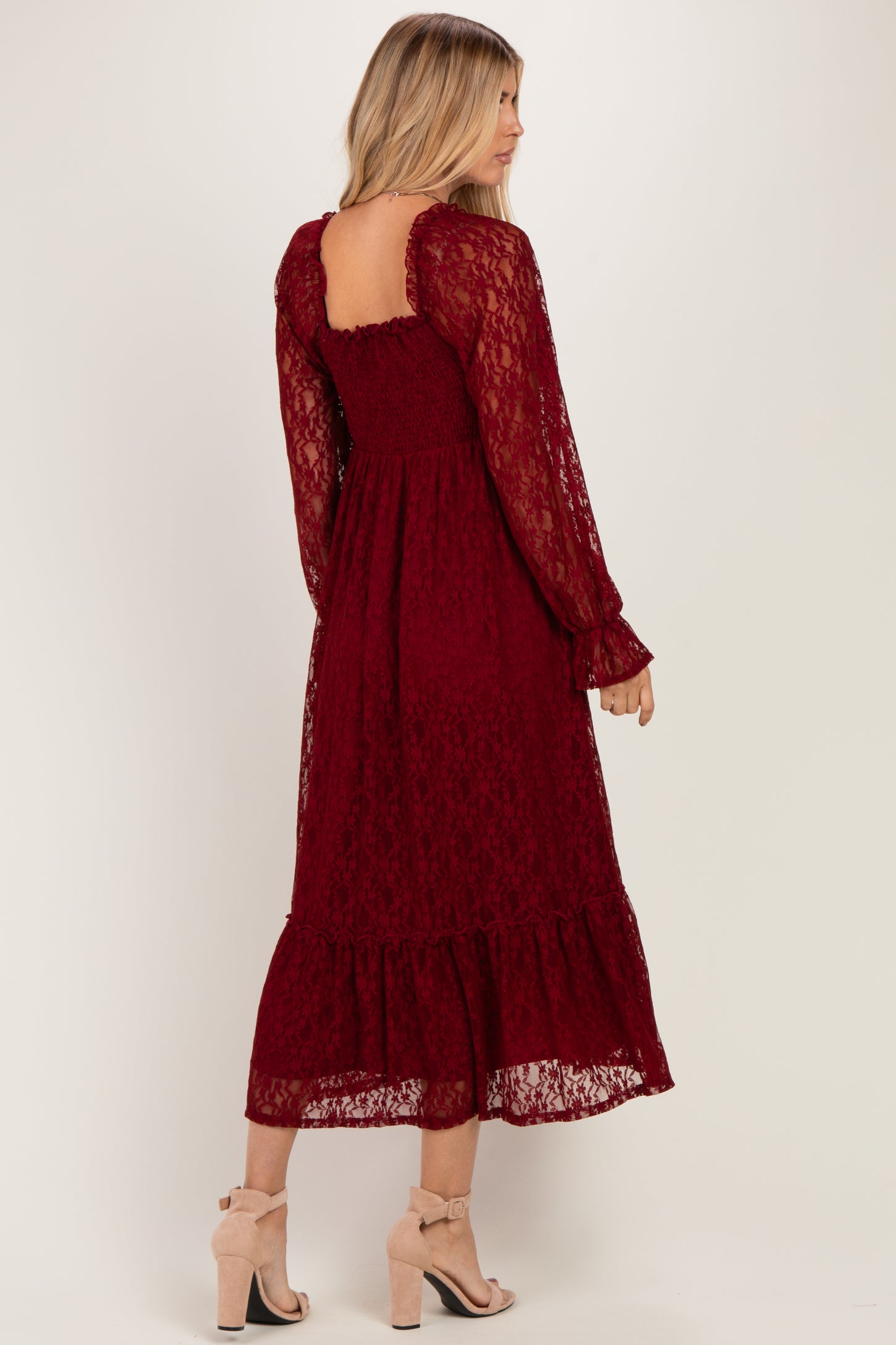 woman wearing a burgundy lace long sleeve midi dress with a ruffled hem and back details