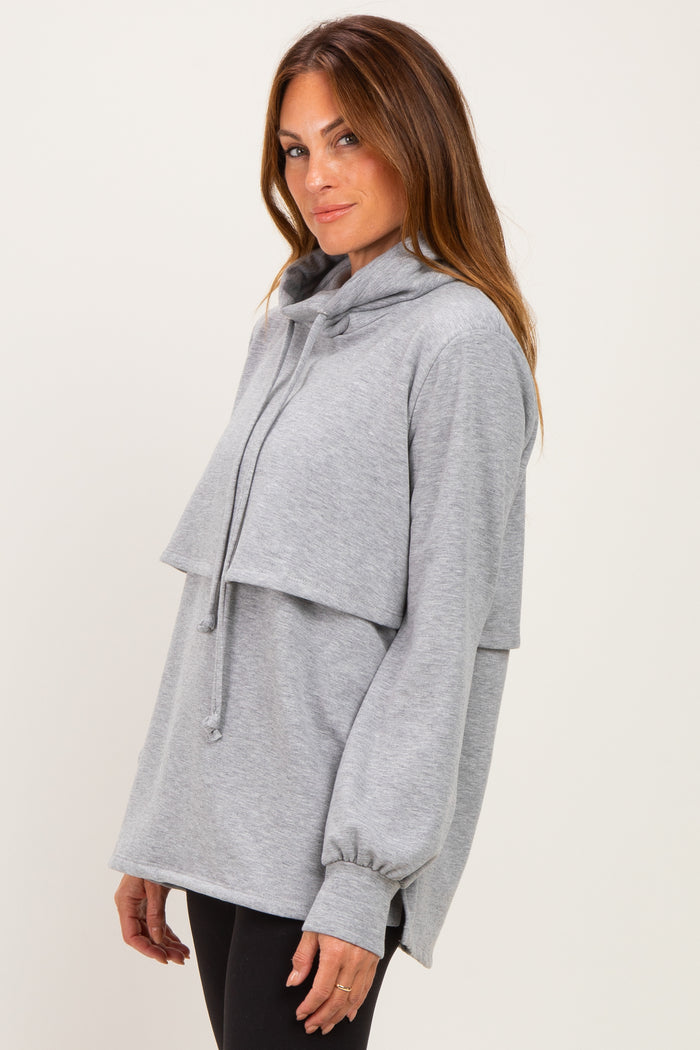 woman wearing a light gray oversized hoodie with a layered design and a drawstring neckline