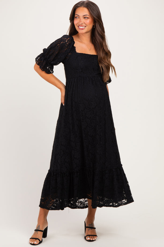 woman wearing a black lace maternity maxi dress with puff sleeves and a baby bump visible