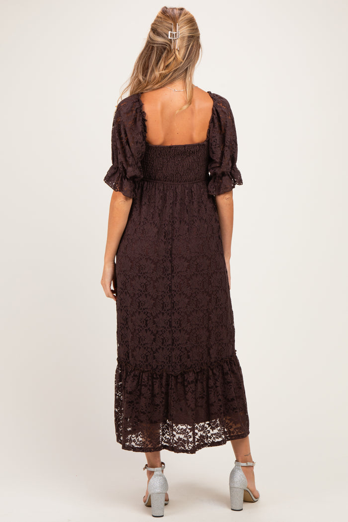 woman wearing a brown lace maternity dress with puff sleeves and a tiered hem, showing a baby bump