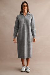 woman wearing a gray long sleeve knit zip-up dress with a collar and standing in sporty sneakers