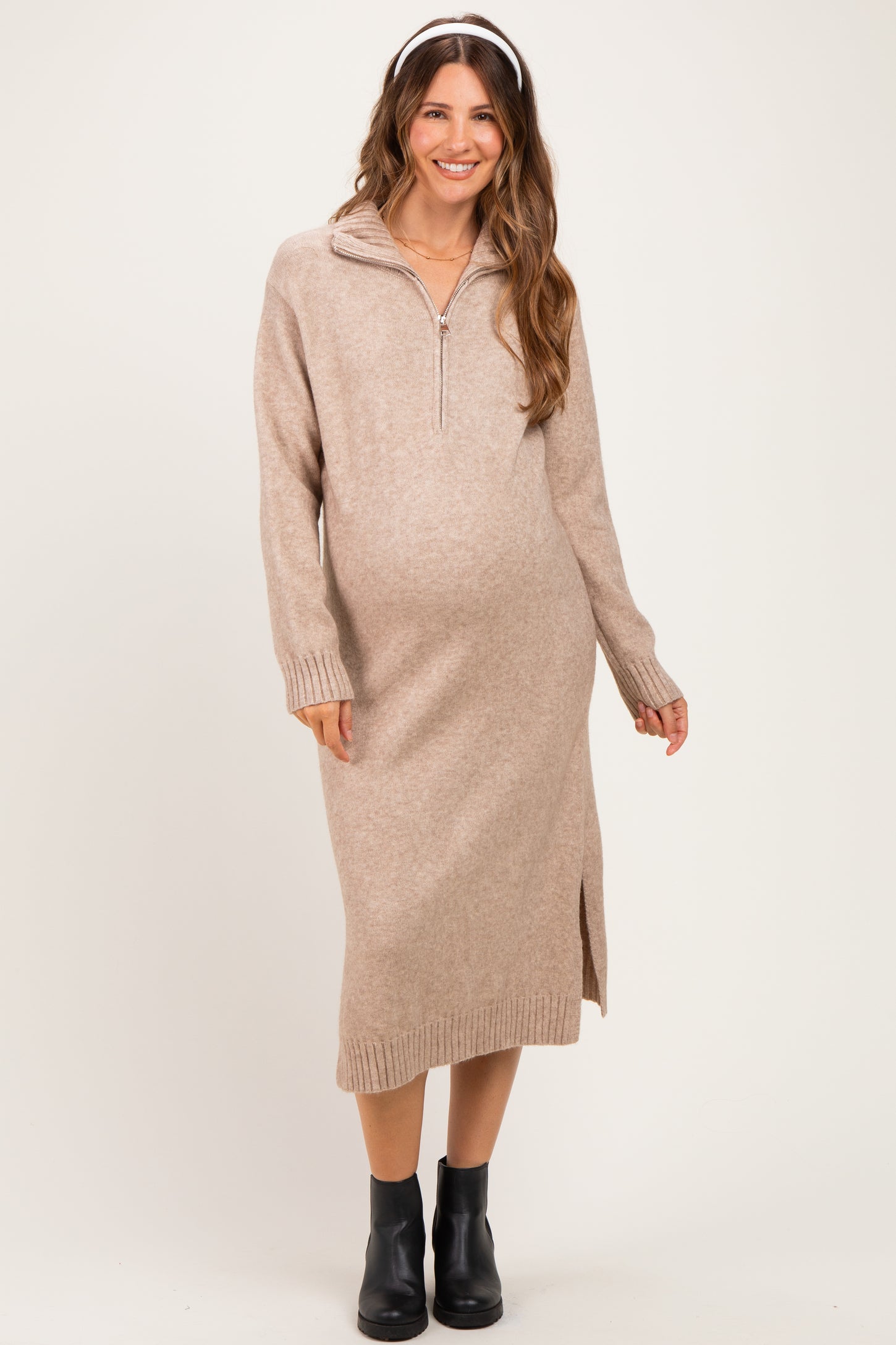 woman wearing a beige zip-up maternity sweater dress with side slits and a baby bump visible