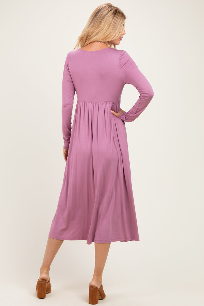 woman wearing a long sleeve pink dress with a fitted bodice and flowing skirt, showing the back view