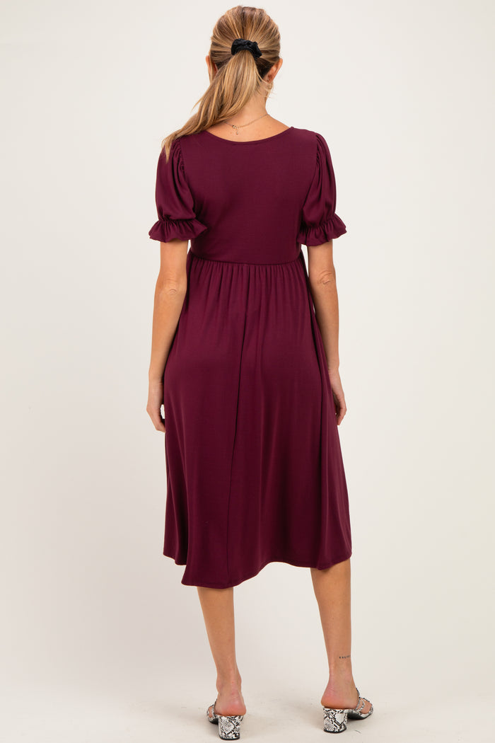 woman wearing a burgundy maternity dress with puff sleeves, showing a flowing silhouette from the back