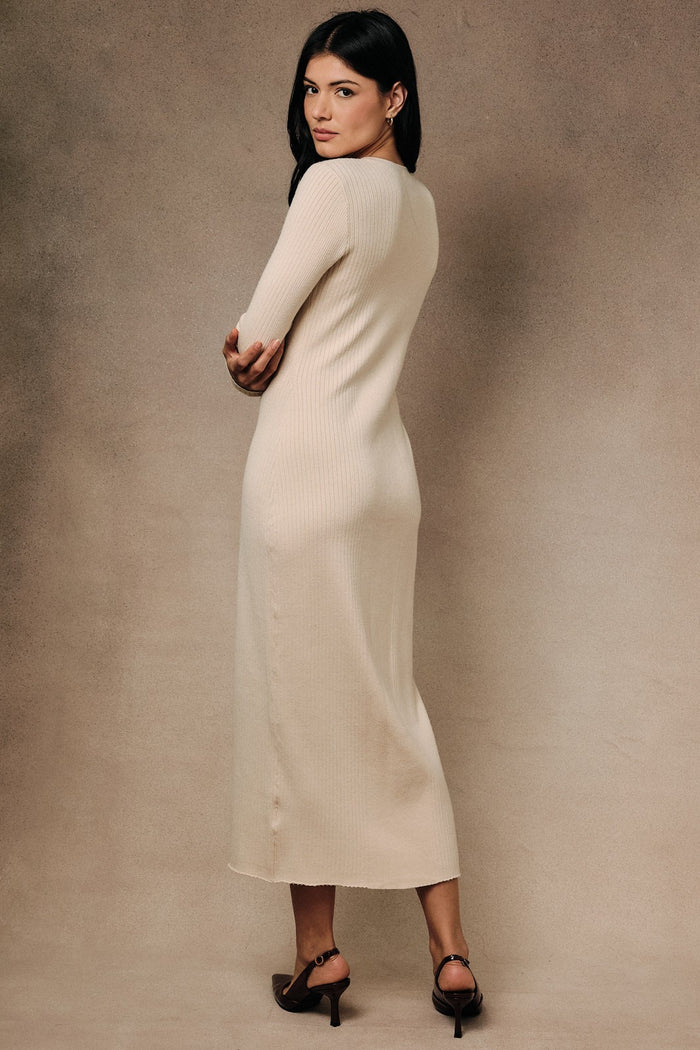 woman wearing a cream long sleeve ribbed midi dress, standing with her back to the camera