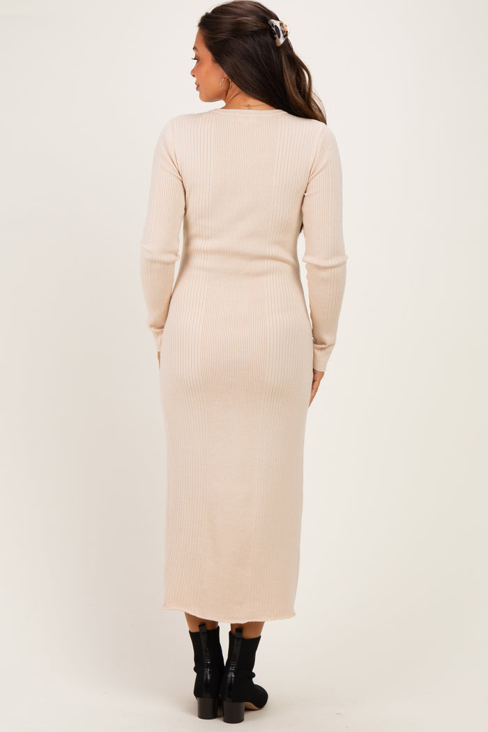 woman wearing a beige ribbed maternity dress with long sleeves, showing a fitted silhouette and midi length
