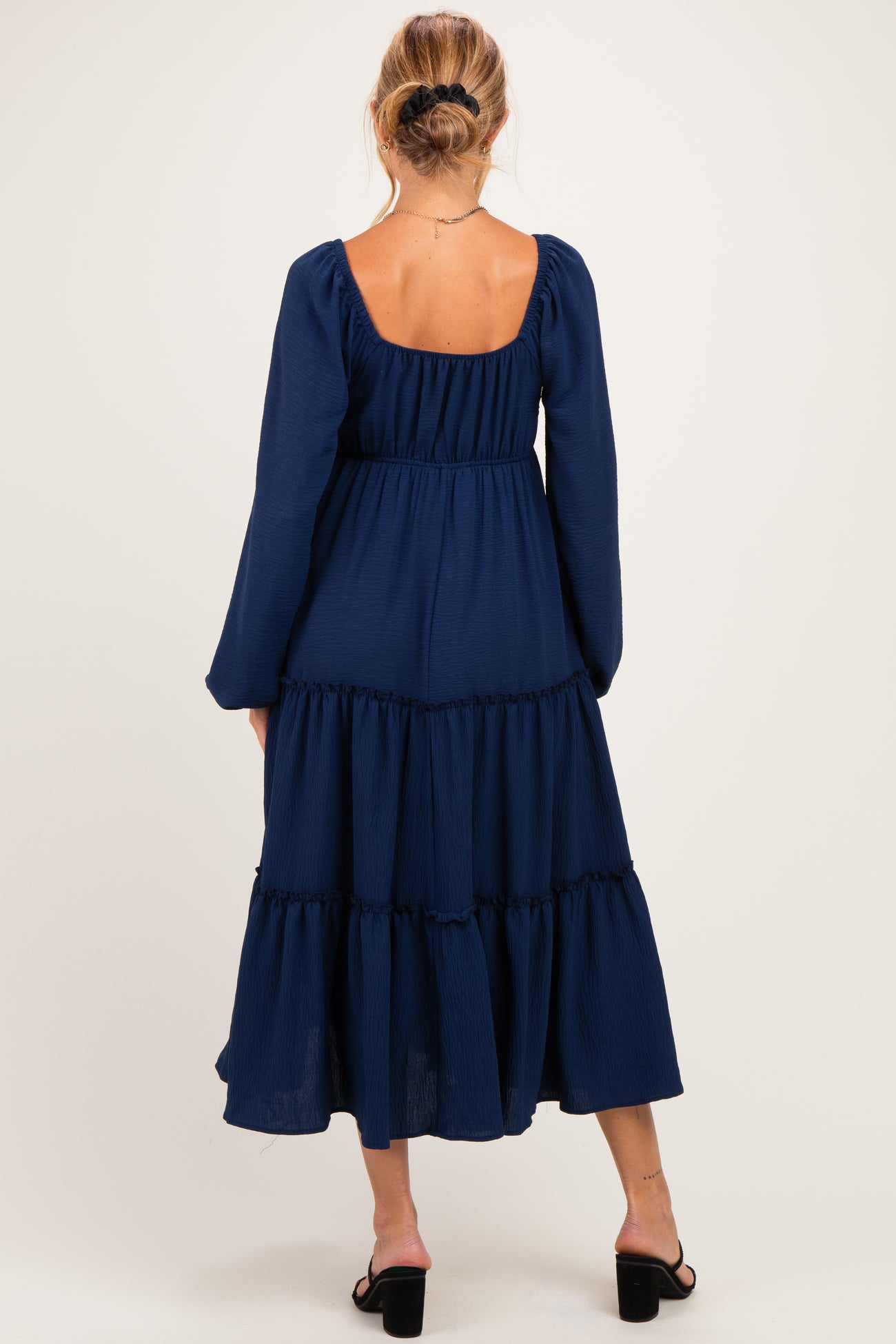 woman wearing a navy blue maternity maxi dress with a tiered skirt and long sleeves