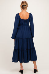 woman wearing a navy blue maternity maxi dress with a tiered skirt and long sleeves