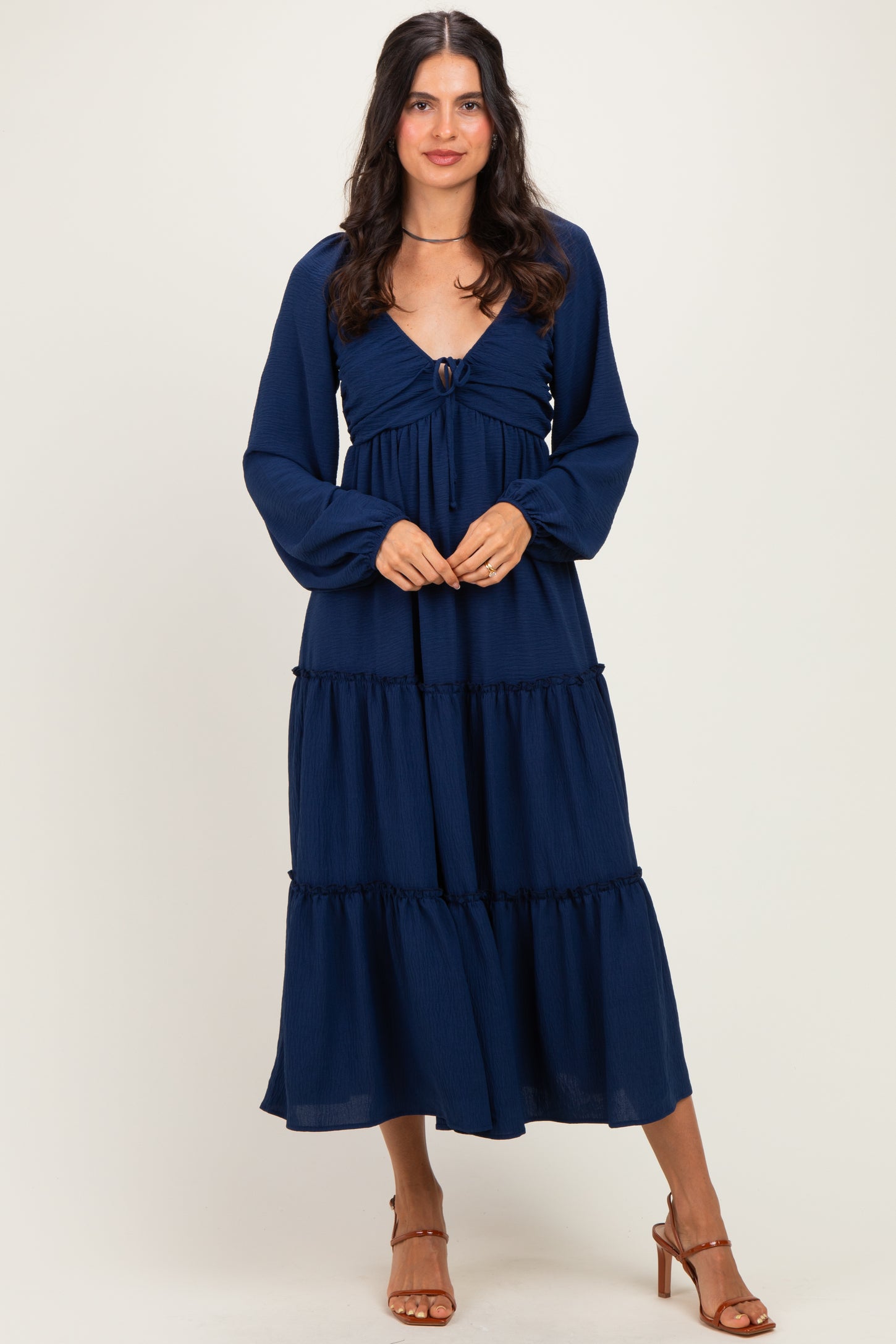 woman wearing a navy blue tiered maxi dress with long sleeves and a front tie detail