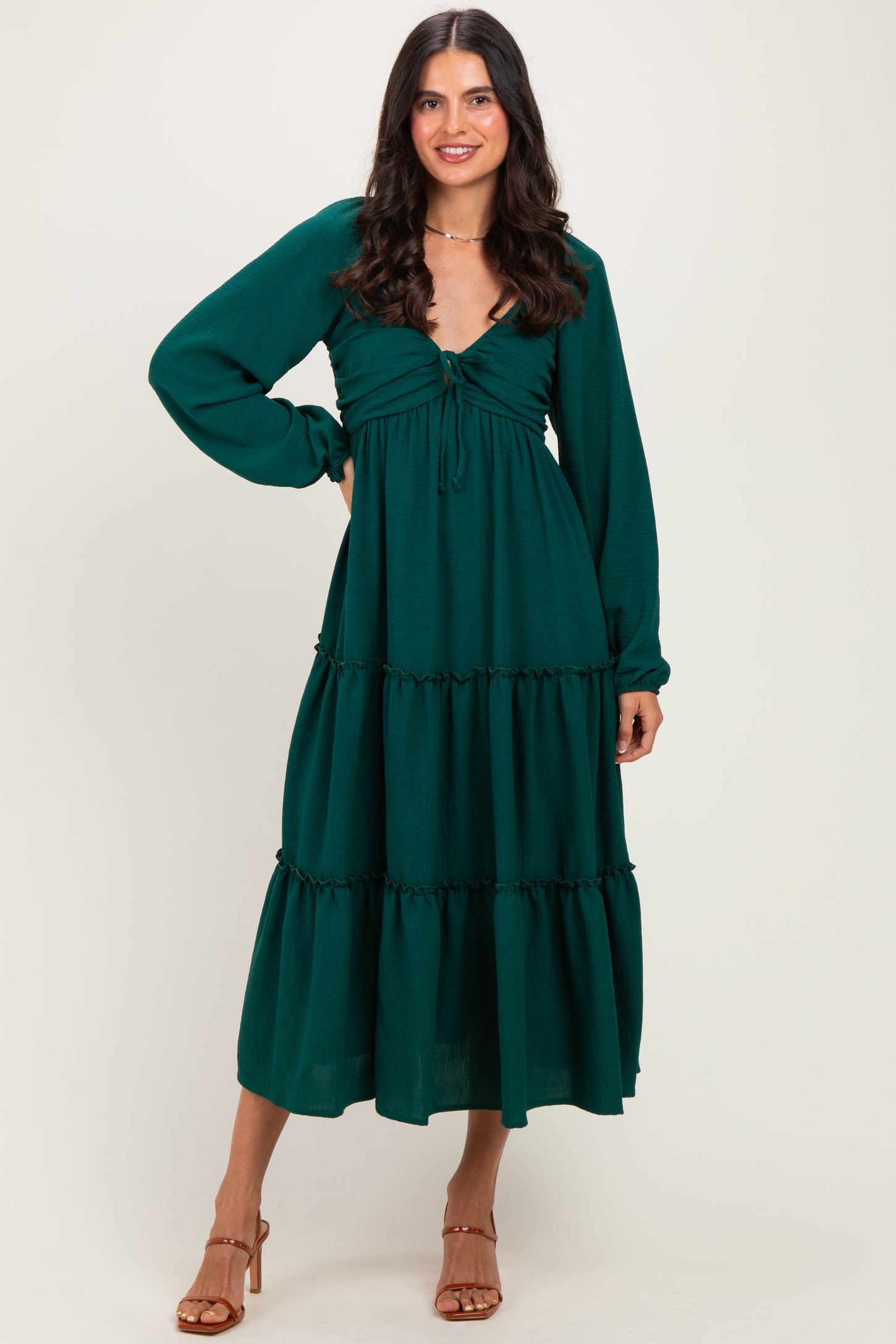 woman wearing a forest green long sleeve maxi dress with a tie front and tiered skirt