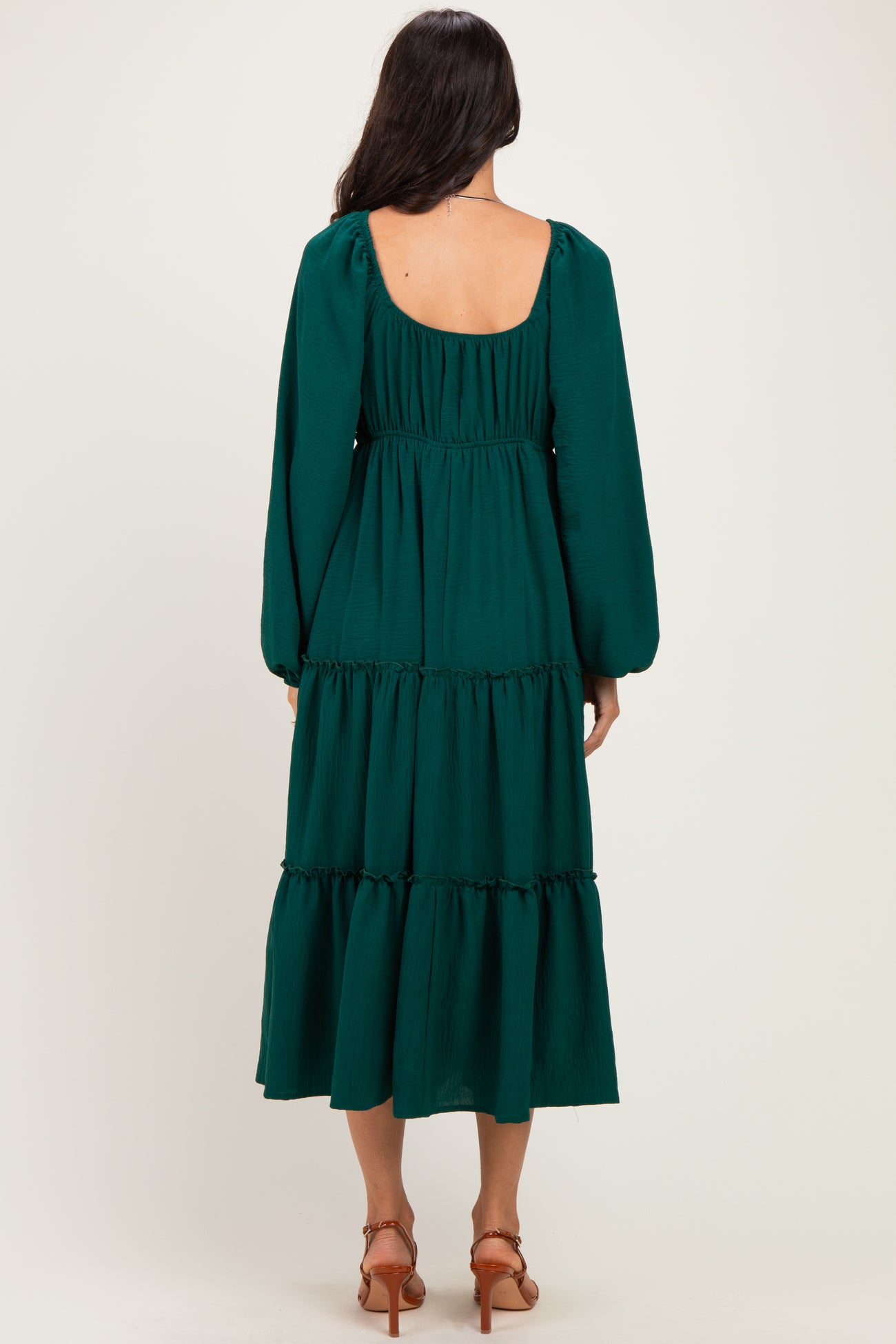woman wearing a dark green tiered midi dress with long puff sleeves and a low back
