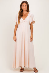 woman wearing a light pink maxi dress with flutter sleeves and a knotted front detail