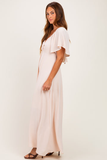 woman wearing a soft pink maxi dress with flutter sleeves and a knot detail at the neckline