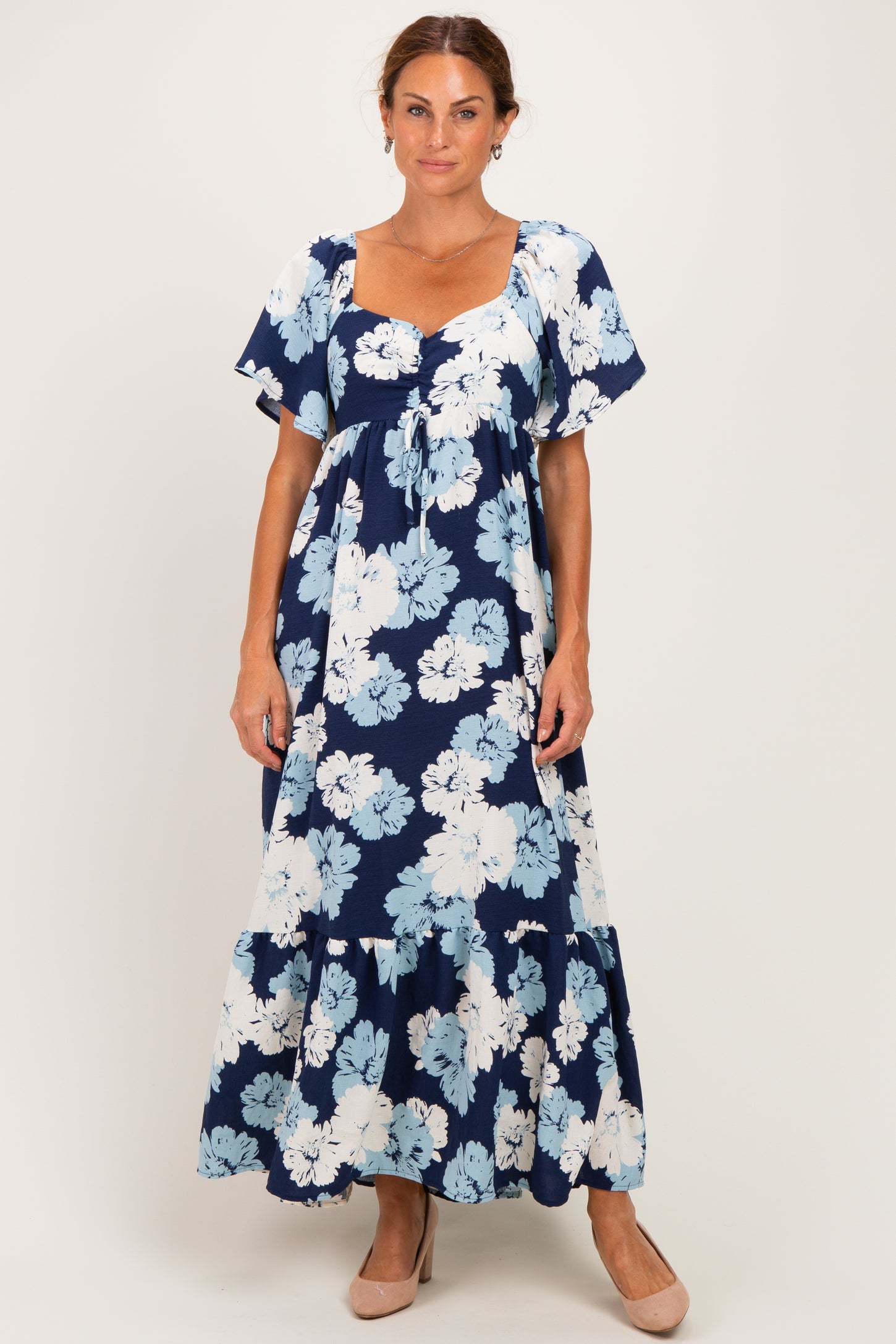 woman wearing a floral navy blue maxi dress with short sleeves and a tiered skirt