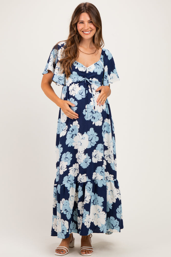 woman wearing a navy blue floral maternity maxi dress and holding her baby bump